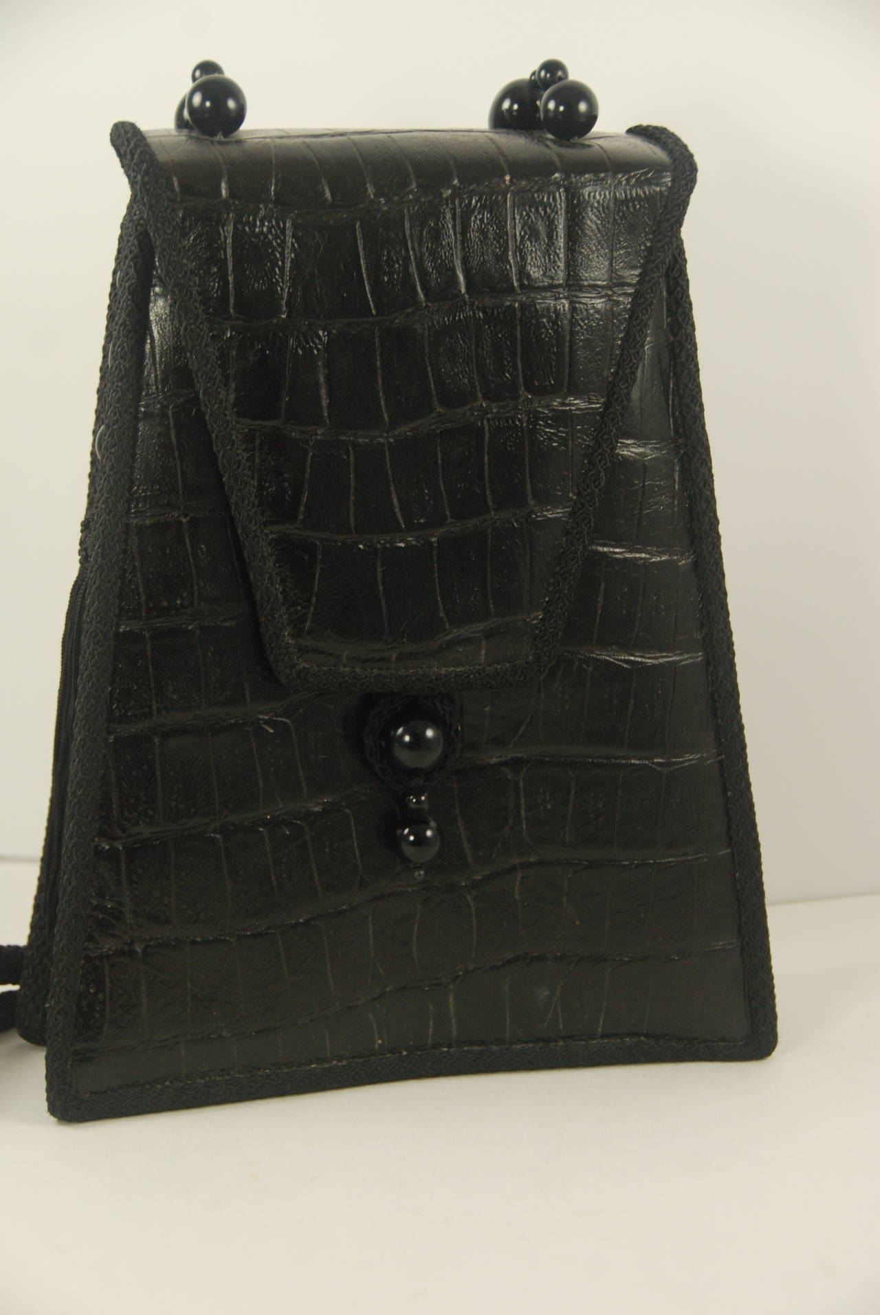Asian inspired Rafael Sanchez alligator shoulder bag with woven silk cord and decorative bead strap. There is also a bead and black silk and bead tassel on the side of the bag that is decorative. Piping on the bag is woven black silk. Inside is