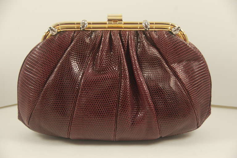 Judith Leiber burgundy clutch/shoulder bag with little frogs that have onyx eyes decorating the gold tone frame. The frogs are silver. THe clasp works well and bag closes securely. There is an optional shoulder strap that folds into the bag when not