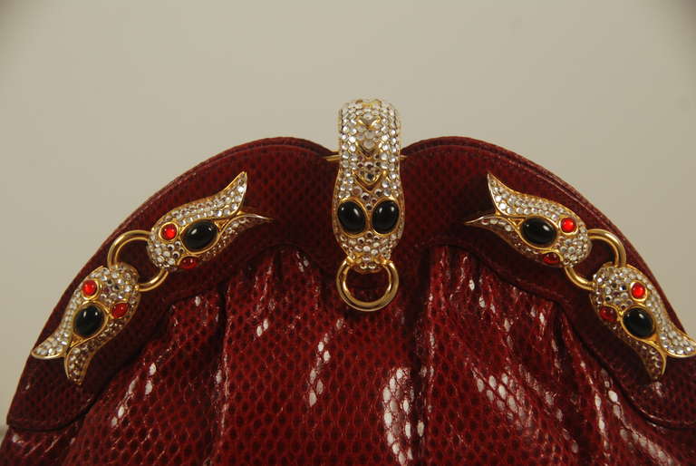 Beautiful red lizard evening bag by FInesse La Model. He clasp is a rhinestone embellished snake head with onyx eyes. There are additional rhinestone embellishments with onyx and red stones. The clasp works well andcloses securely. There is an