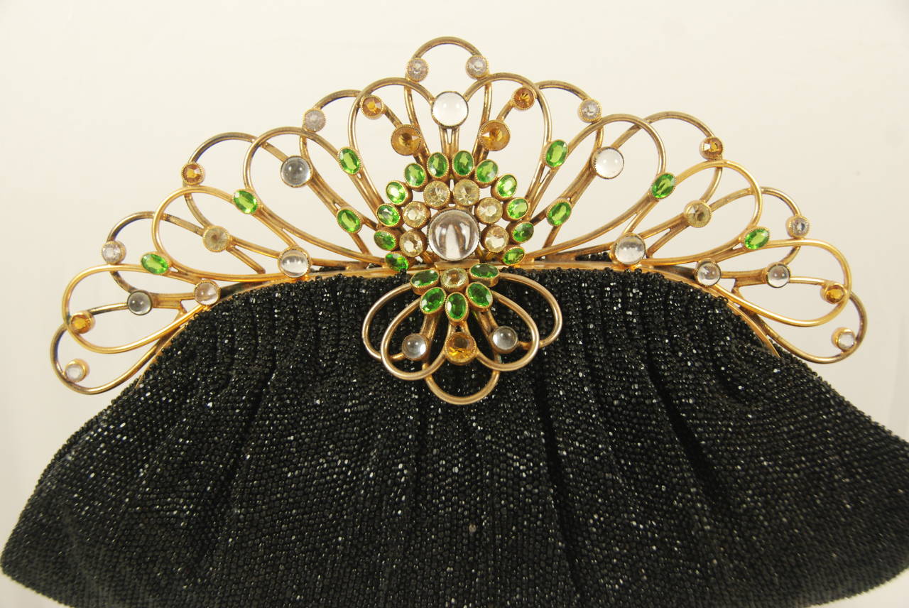 Elegant Josef black beaded evening bag with jeweled and wire work fame. The ornate frame mimics a tiara. The stones are green, golden, and clear.There are cut stones and cabochons. Inside is lined with cream colored satin. The original comb and