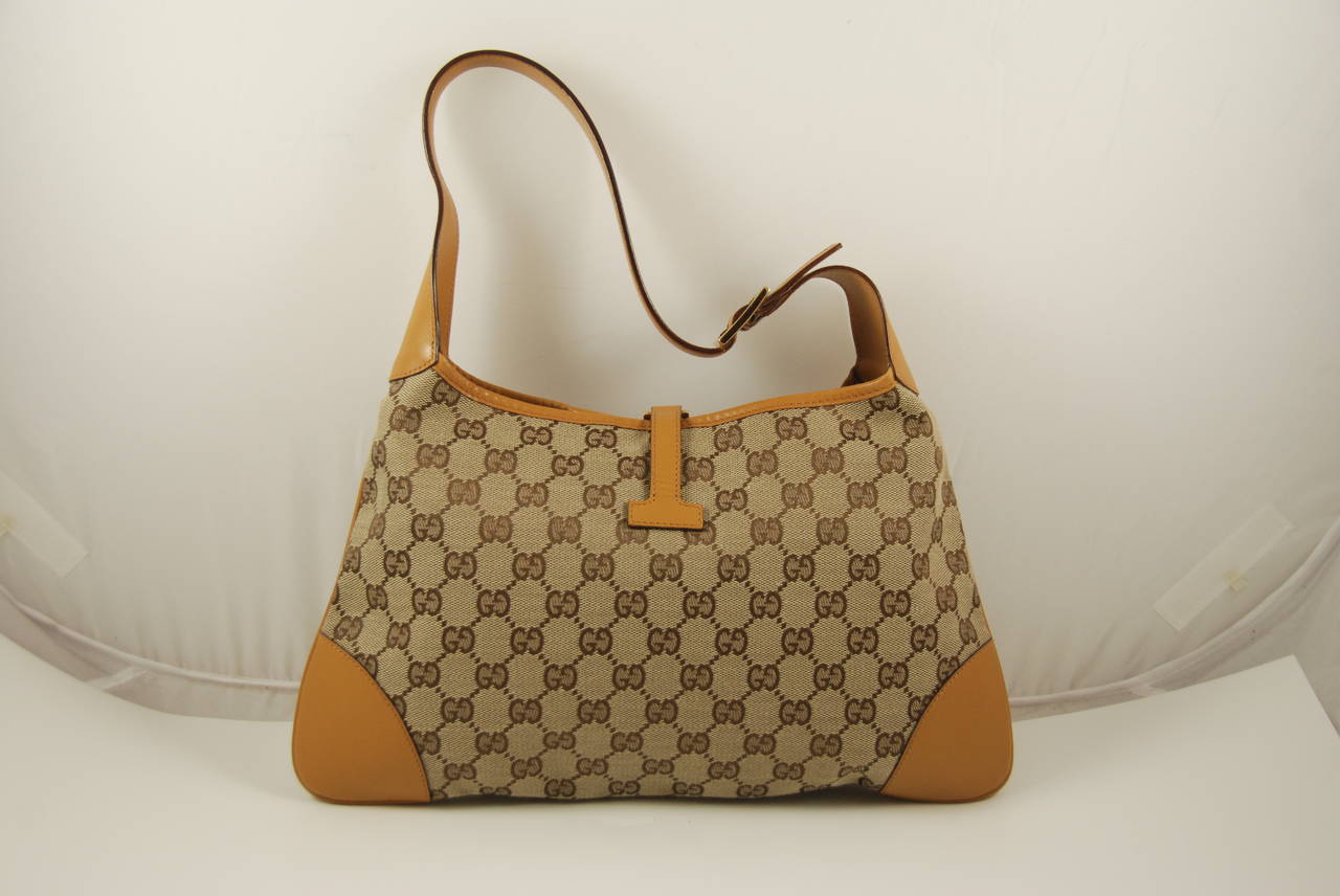 Gucci Jackie bag in a golden mustard yellow trim, the monogram canvas is in alight brown. Lining is a deep brown and has one zipper compartment. Bag can fit snugly under the shoulder or carried as a handbag. The strap has a 7