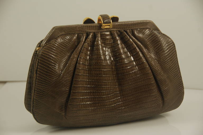 Beautiful Judith Leiber clutch in Karung (lizard). It is hard for me to describe the color, you can either call it dark taupe or mocha, either way it is a great neutral color that will go with about everything. The skins are supple and glossy. There