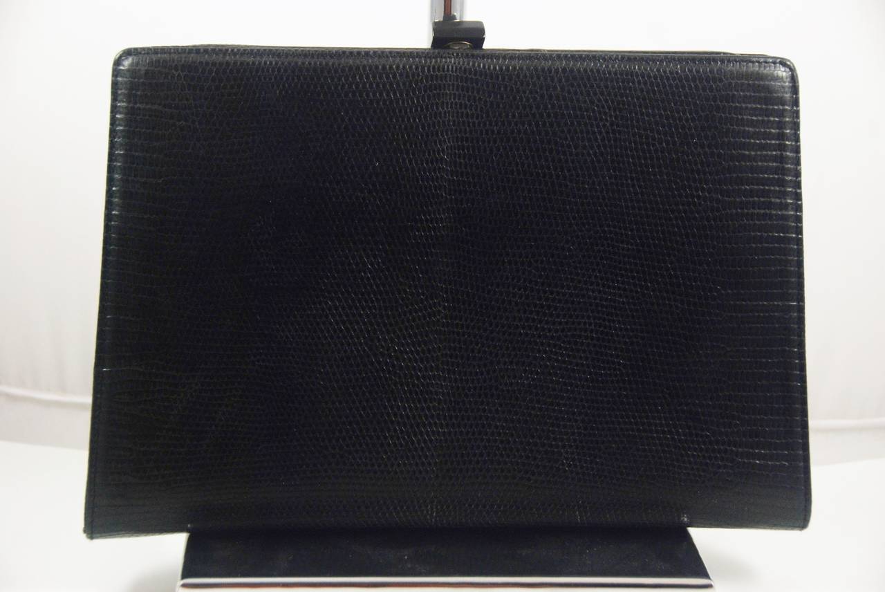 Sleek and smart, a timeless classic, black lizard clutch by Bottega Veneta. Inside has one zipper section. The inside is lined in smooth black leather. Clasp works well and bag closes securely with a loud click.