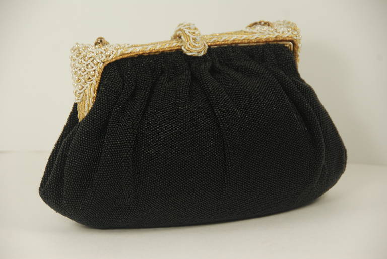 Fabulous example of a mid century beaded evening bag from France. In excellent condition, the body of this bag is beaded in tiny black beads. The wide frame is beaded in gold and white beads with pearls in an art deco inspired pattern. Lining is