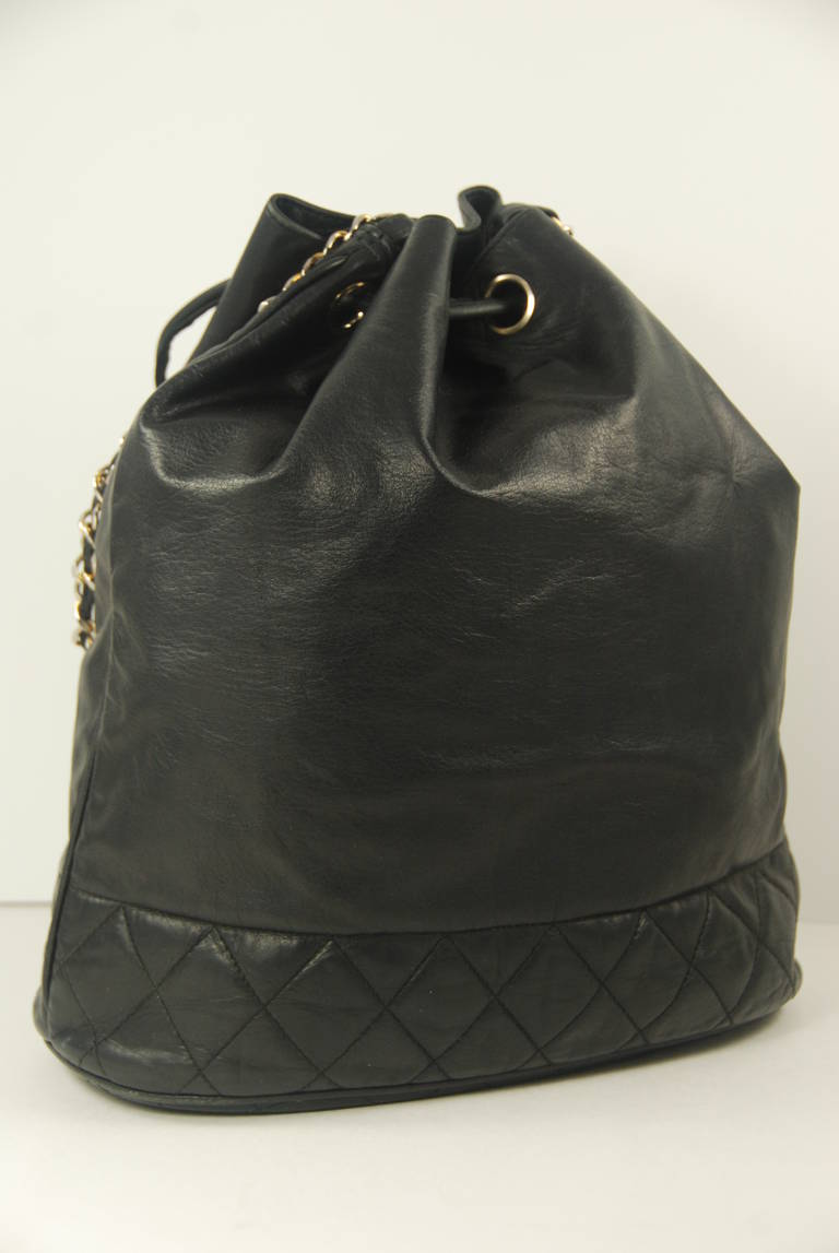 Chanel bucket bag from the late 1980s to early 1990s in black lambskin. The leather is very soft and supple. Closure is by leather drawstring. Inside there is an attached leather clip for your keys. The clip part has been replaced. The icon was