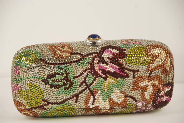1990s Judith Leiber minaudiere  with multi color leaves against a clear rhinestone background. The brilliant colors used for the leaves are red, pink,two shades of green, bronze and lilac. All stones are present and sparkle. There is a silver chain