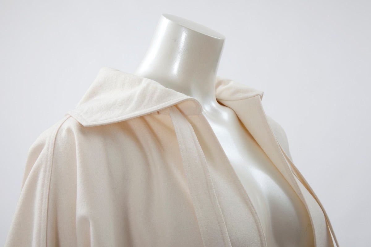 Timeless Courreges off white light wool coat/cape. Raglan sleeves, side pockets and belt-like collar knot (see images 4 & 6). Though labeled a Courreges size 00, the coat will easily accommodate any size. 

Fits approx. : S/M/L/XL 

Measurements