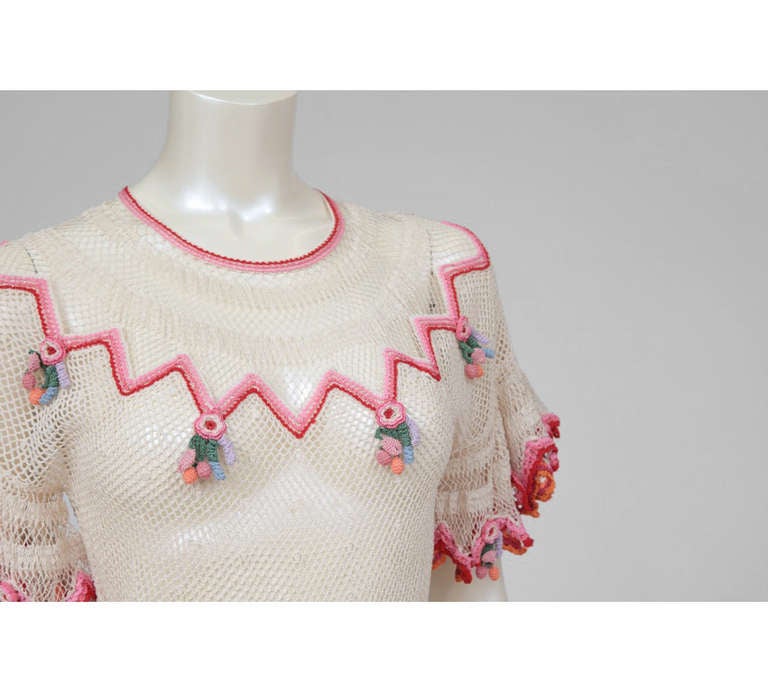 Amazing and colorful 1940's dress entirely made in crochet. The volume of crochet work is impressive : sleeves and skirt were done as full circles. Little clusters of stylized fruits and/or flowers hang from each sleeve and around the hem. The dress