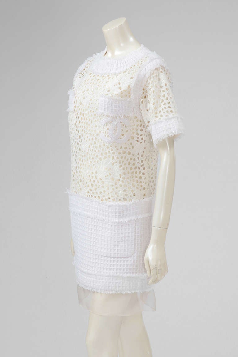 A short summer dress by Chanel from the Resort Collection 2011. White cotton see through guipure and light cotton and silk tweed. The top is not lined. The dress closes with a back painted metal zipper and a hook. Note that the former owner has