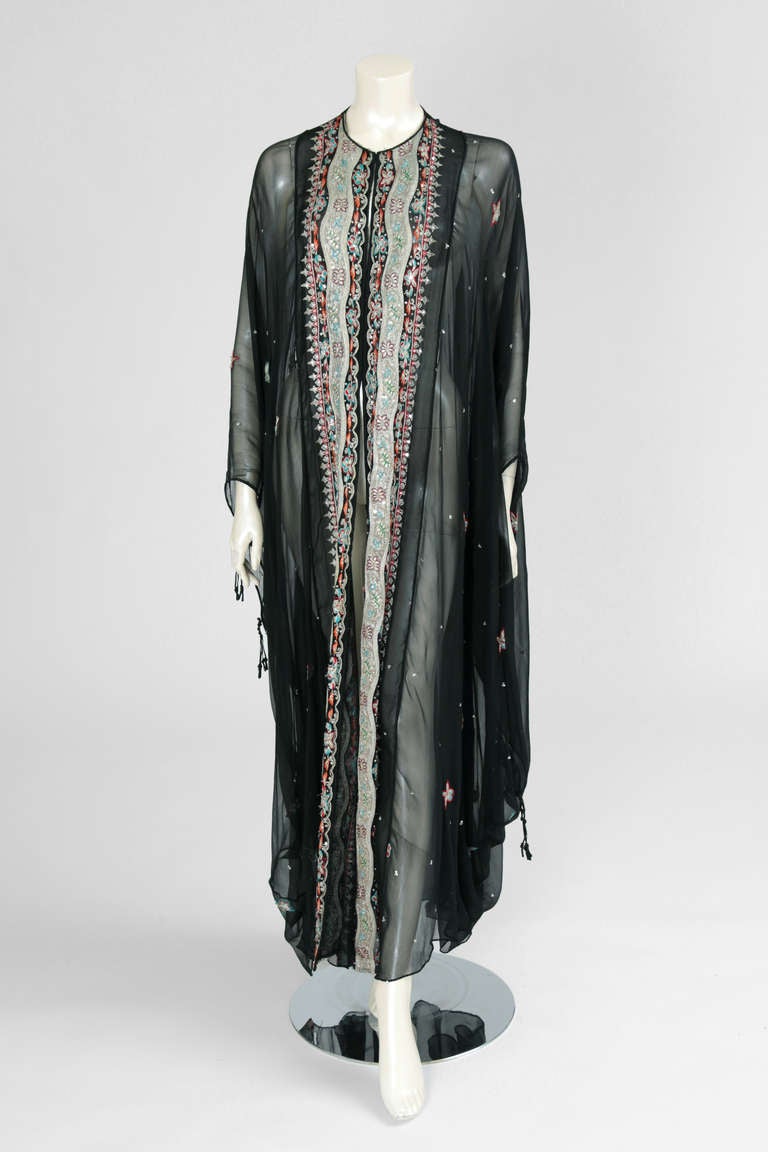 Very representative and collectible Thea Porter Couture caftan dating from the seventies. This see-through caftan-dress is made of black silk chiffon with very intricate and refined silver metallic thread embroidery (probably antique Indian or