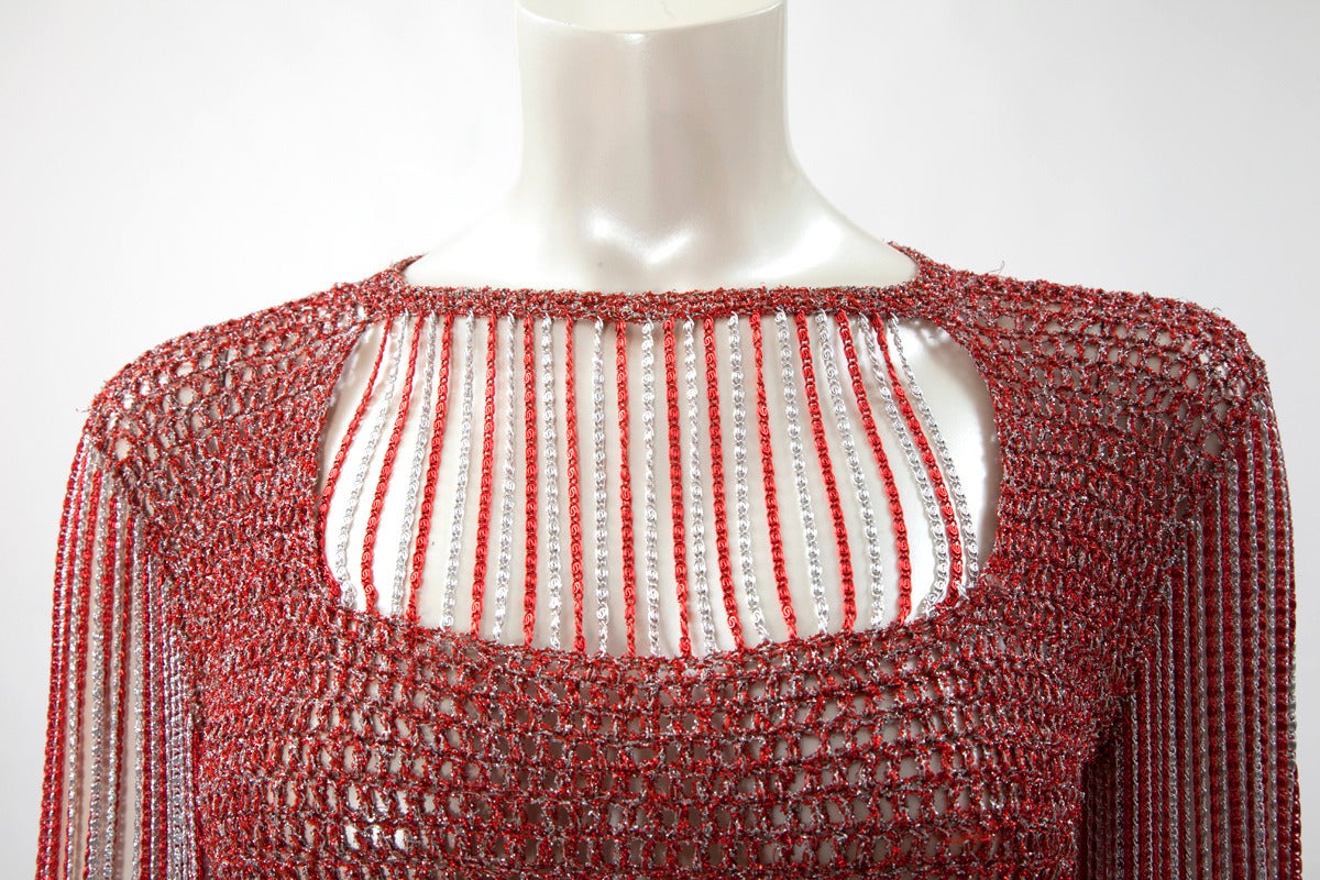 Remarquable ensemble deux pièces Azzaro des années 70, composé d'un top en crochet rouge et argenté et d'une jupe longue en jersey poly/rayon noir. Le top, avec son décolleté rectangulaire sexy sur le devant et dans le dos, est réalisé en maille