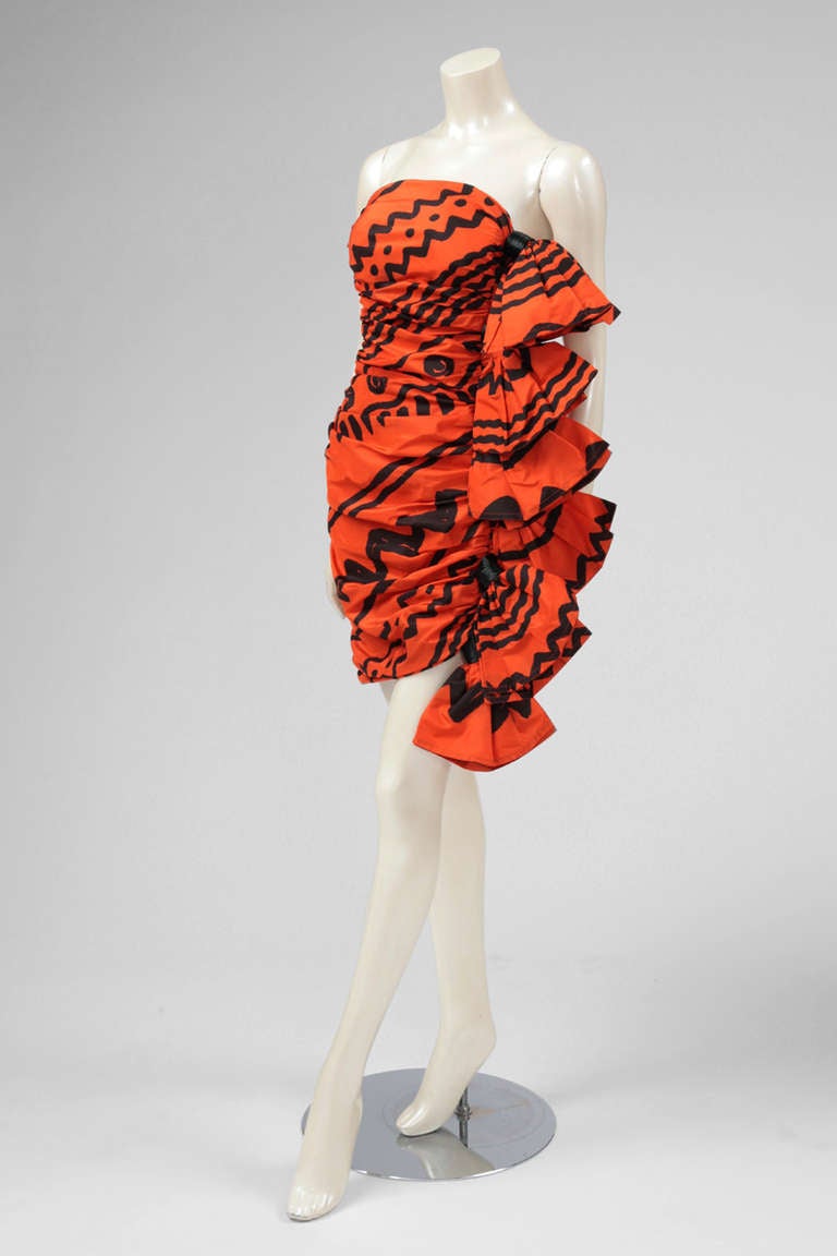 Outstanding summer 1985 Angelo Tarlazzi cocktail mini-dress with exuberant knotting and tribal print. The dress is entirely draped and its right side features half-knots. The knots are held with genuine black raphia. Zip closure on the right