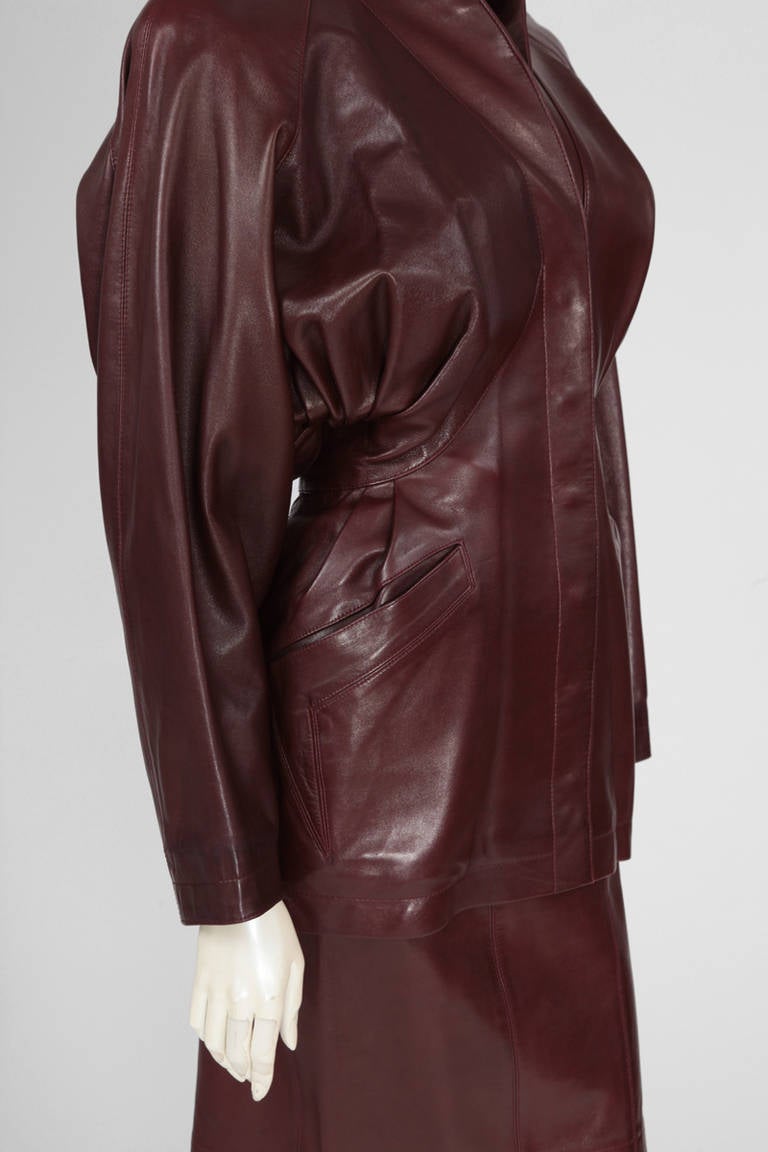 One of Alaïa’s late 80's - early 90's piece in burgundy lambskin leather. Two piece suit with a long tailored draped jacket with relaxed shoulders. Wrapped trench coat belted detail in the back (see pictures 3 & 4). The jacket has press-stud closure
