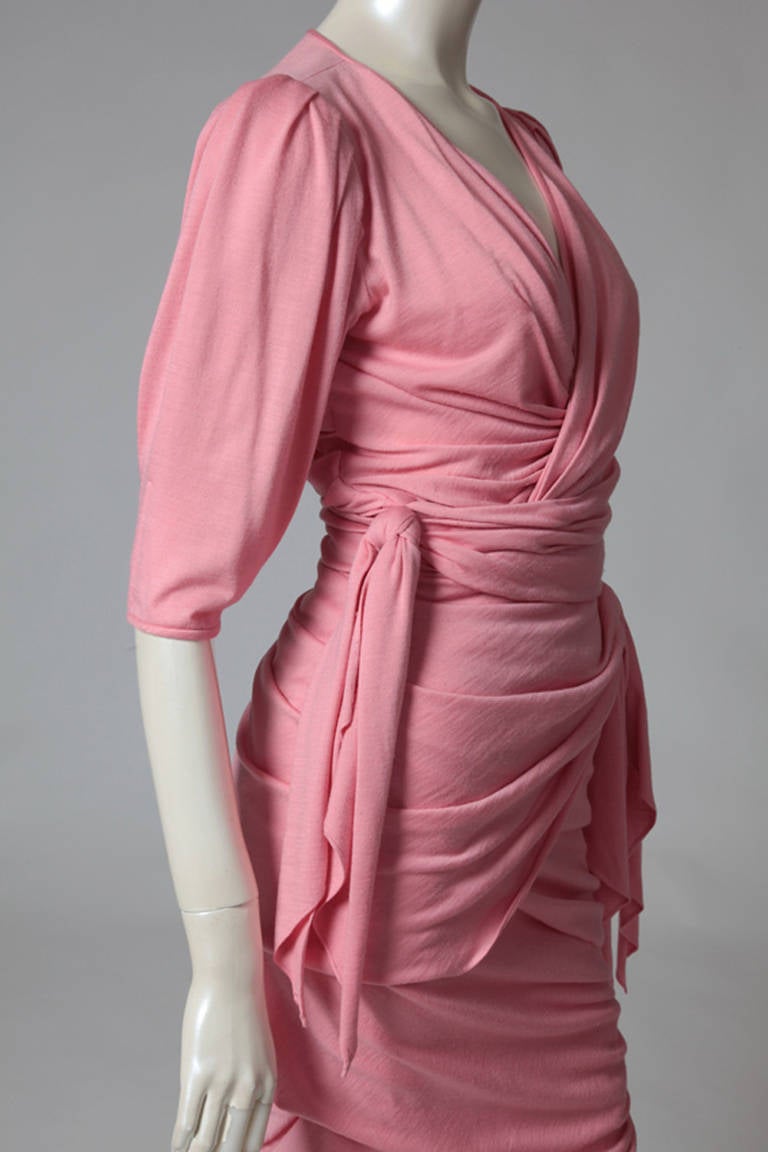 Elegant and sexy 80’s Ungaro pink wool draped dress. Bows-knots on both sides of the belt accent the bodice and the waist. V neck cleavage and zip closure on the left side. As the fabric is stretchy, the dress will accommodate a size small, medium