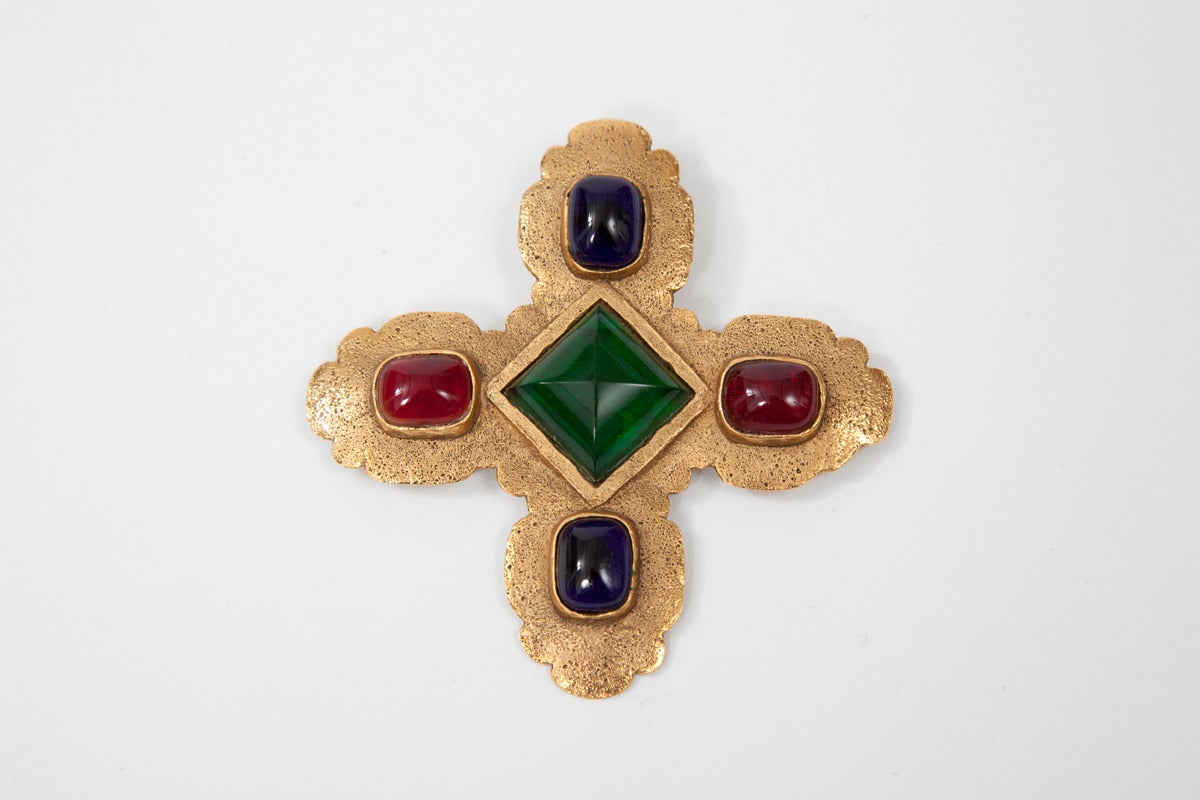 This vintage Chanel brooch features a Maltese cross design with midnight blue, cranberry and green color Gripoix cabochons glass in a gold-toned setting. The brooch is signed 