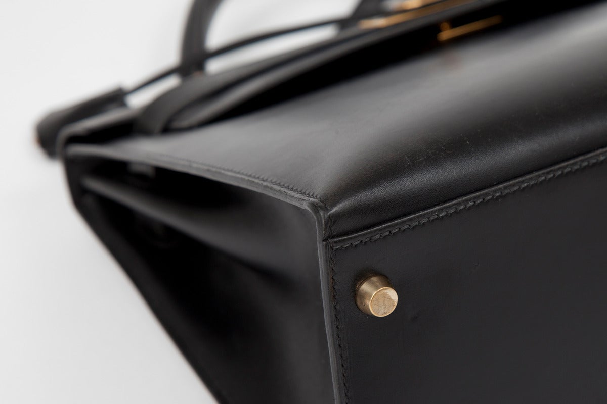 Timeless 1995 Hermes Kelly Sellier handbag in black box calfskin with gold-plated hardware. One zip pocket and two patch pockets. The bag comes with its original Hermes padlock, two keys, clochette and dust bag. Detachable shoulder strap. Blind