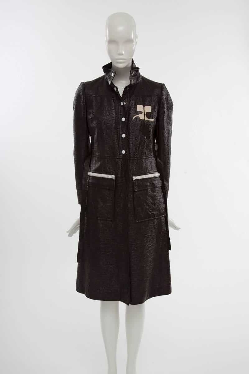 Timeless iconic Courrèges vinyl trench coat in dark brown color. Two oversized front patch pockets with white plastic zip and painted metal snaps down the front. Non original brown leather belt. The trench features the typical removable silky rayon