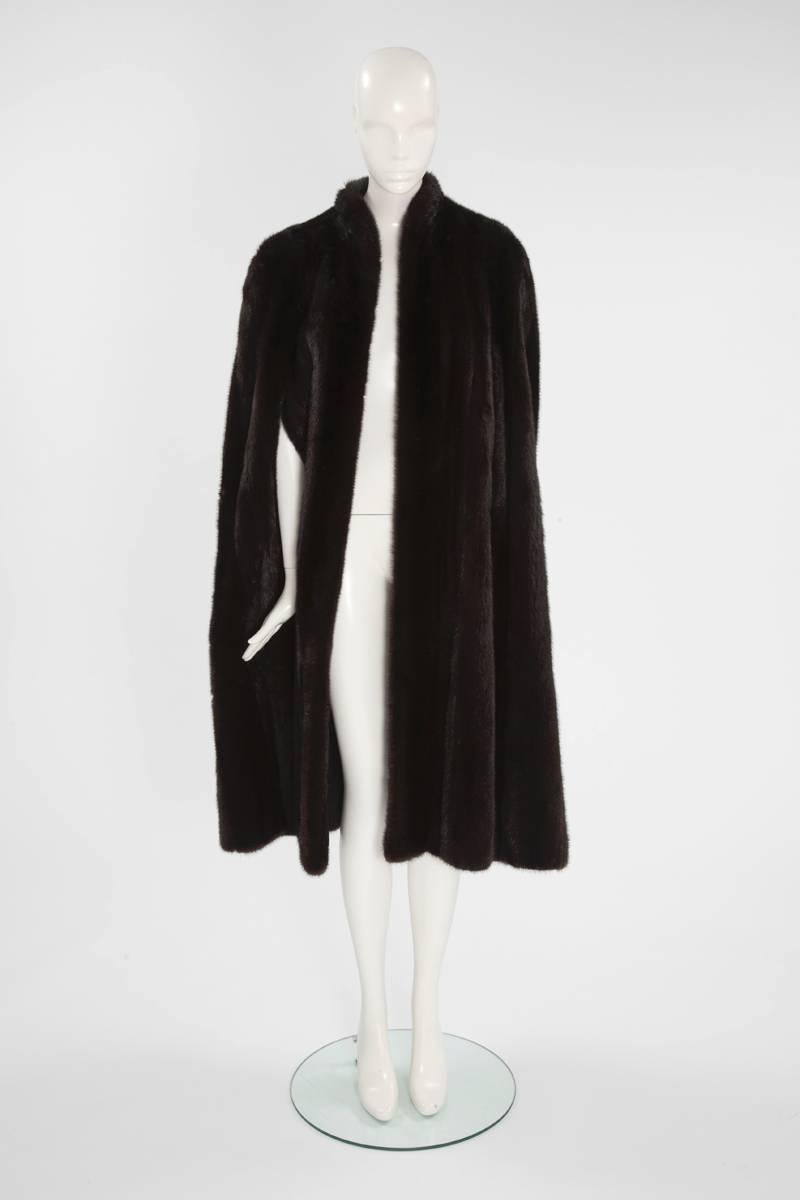 Inject some haute couture into a winter wardrobe with this rare 70's Dior cape. Made of dark brown mink, the cape fastens with hooks to the front and features a pretty small mandarin collar and overscale pockets. On the sides, subtle bands of