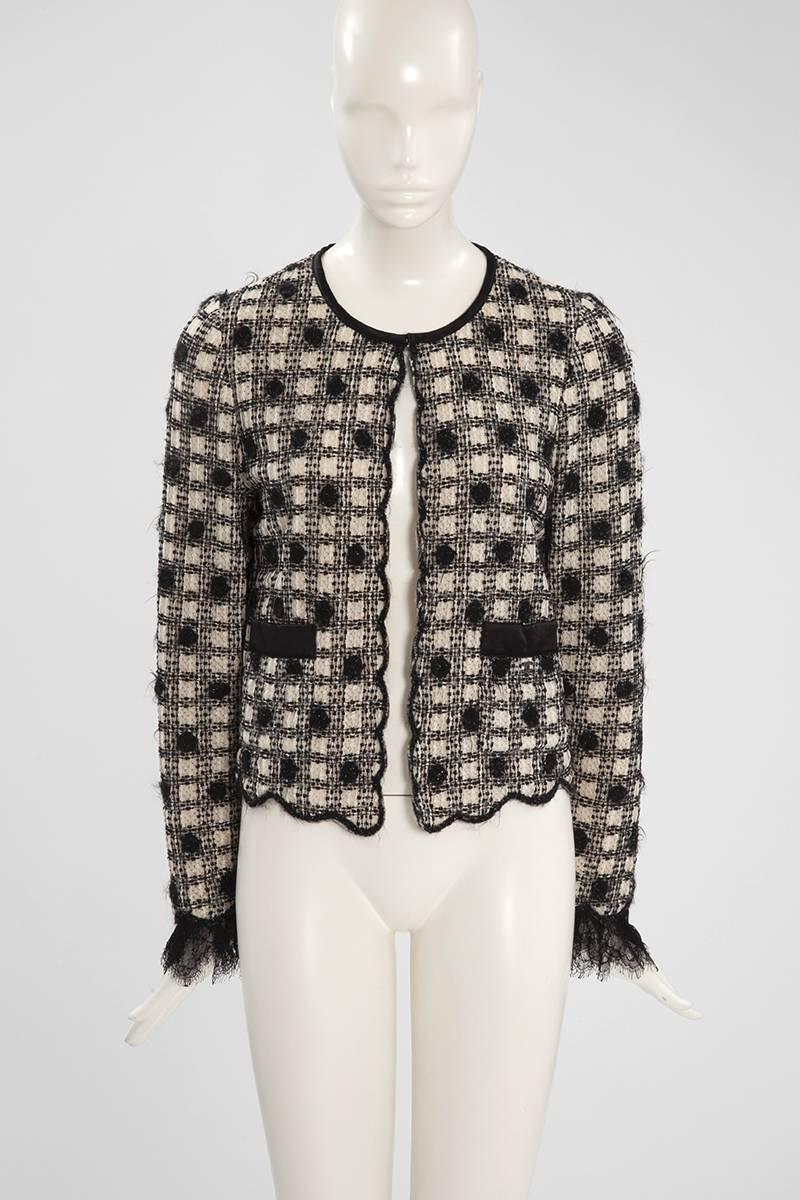 Chanel puts a playful spin on a classical little jacket/cardigan. Crafted from off-white cashmere which is covered by a pretty cream and black 