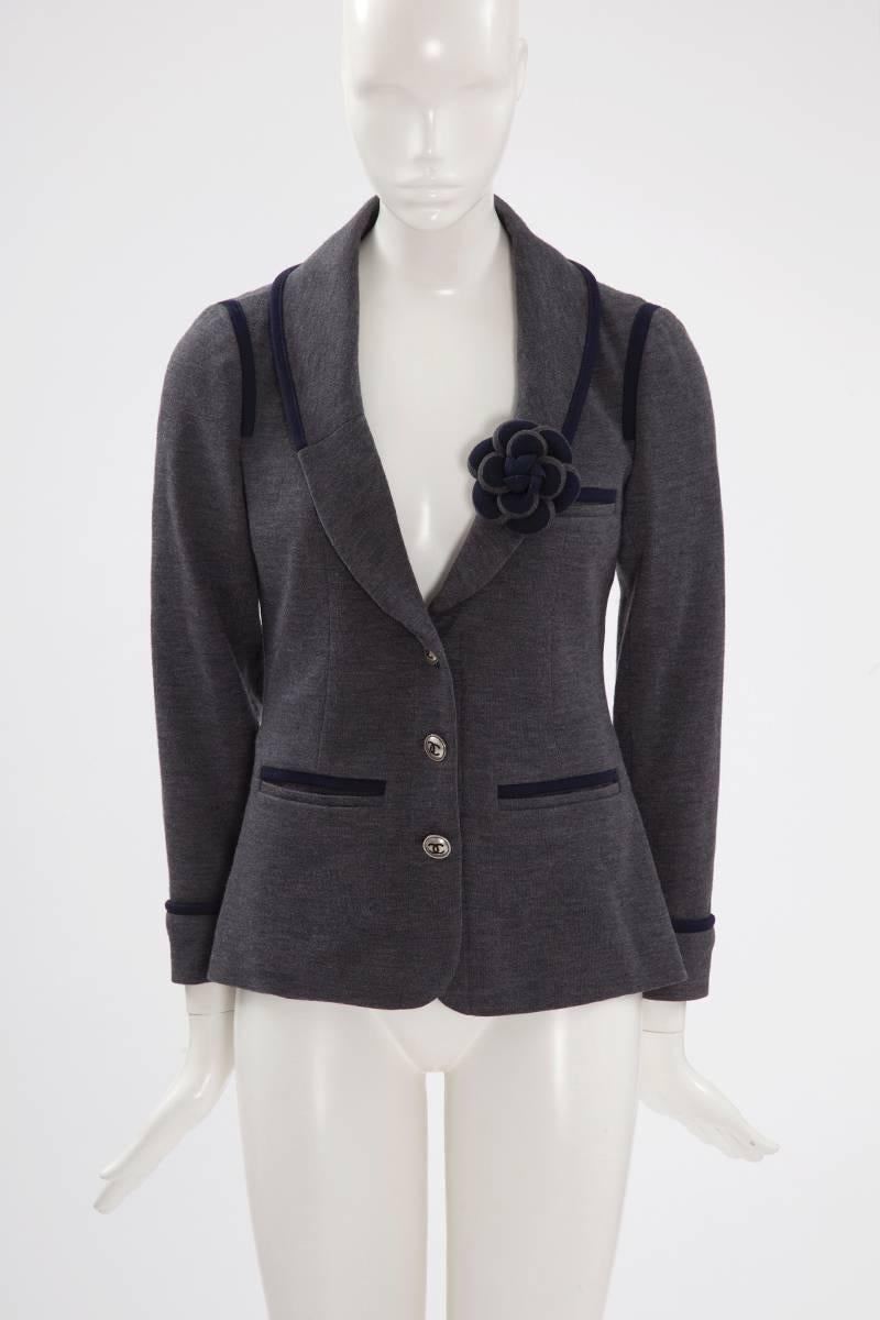 This unusual Chanel blazer is tailored from grey comfy sweatshirt wool and is enhanced with navy blue finishes, partially lined in grey silk. The slim-fit style is perfectly proportioned. The jacket closes with tree large metal logo buttons down the