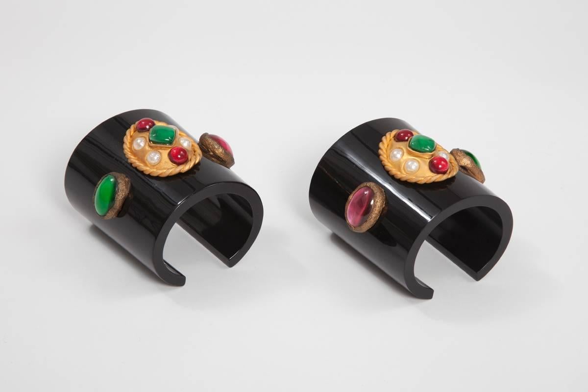 Impressive unsigned Chanel black acrylic cuffs bracelets dating from the 90's. Both cuffs are decorated with colorful resin stone-like cabochons and faux pearls in gold metal setting. The open-ended design (slightly conical) of these incredible
