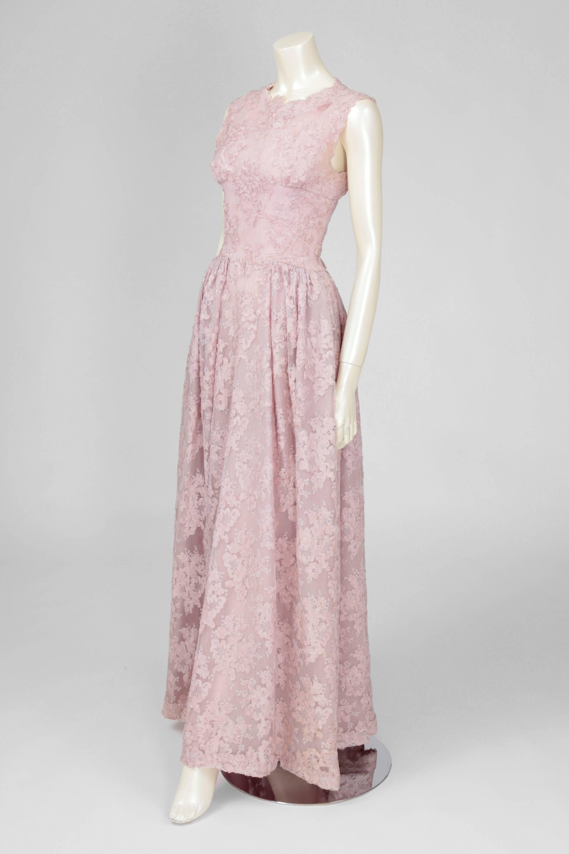 This wonderful handmade late 50’s - early 60’s gown has been crafted from delicate pinkish light lilac lace with matching organdy lining. The sleeveless dress features a round neckline with scalloped edges enhancing in this way the feminity of this