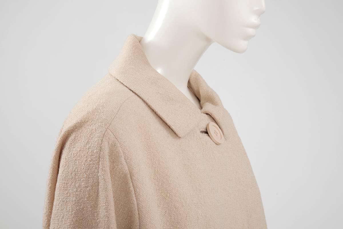 This elegant late 50’s - early 60’s Jacques Heim beige nubby wool coat is perfect for any daytime events or simply for work. Spread collar, raglan sleeves cuffed at the wrist and pockets on the hips complete this modern midseason silhouette. The