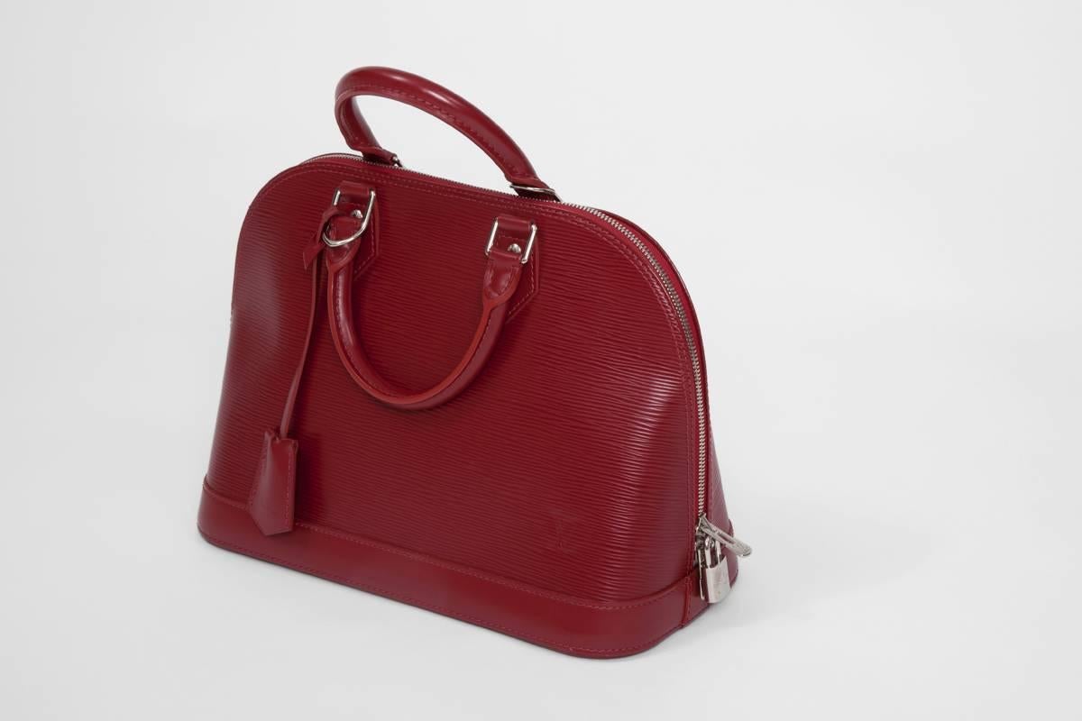 This Louis Vuitton “Alma” PM handbag is a chic and a refined bag perfect for your everyday use. Made of Louis Vuitton’s signature rubis red “Epi” leather, the bag features a structured dome-like shape and has protective base studs. The bag closes