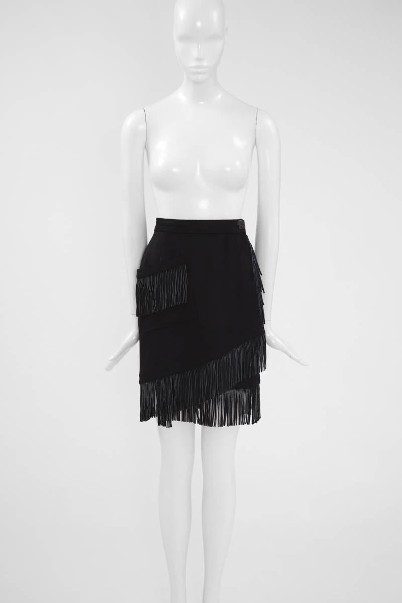 Stunning early 90’s YSL black soft wool wrap skirt. This unusual piece is edged with rows of swinging black suede fringes, found as well on the single large pocket, thus creating a chic western look. The skirt has an asymmetrical hem and closes with