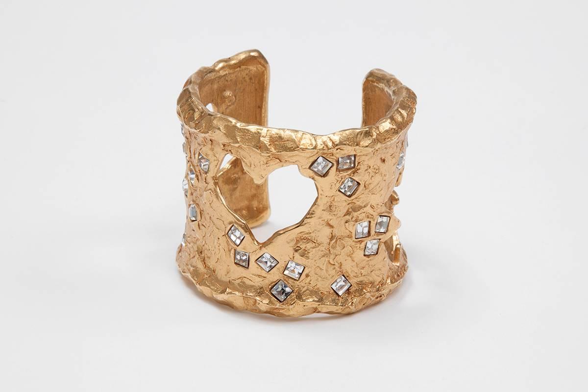 This signed Christian Lacroix gold-plated brass and rhinestones cuff is the perfect statement accessory ! Open-ended, the cuff is enhanced with cool heart, star and cross cutouts. Wear it with daytime looks or party dresses alike.

Dimensions : 