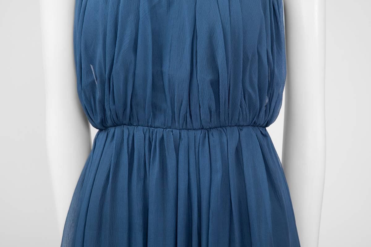 A wonderful example of early 60’s couture, this halterneck steel blue dress will fit perfectly for a wedding or any party event ! Constructed both in silk and satin silk, this piece features a bustier bodice which is covered with two softly ruched