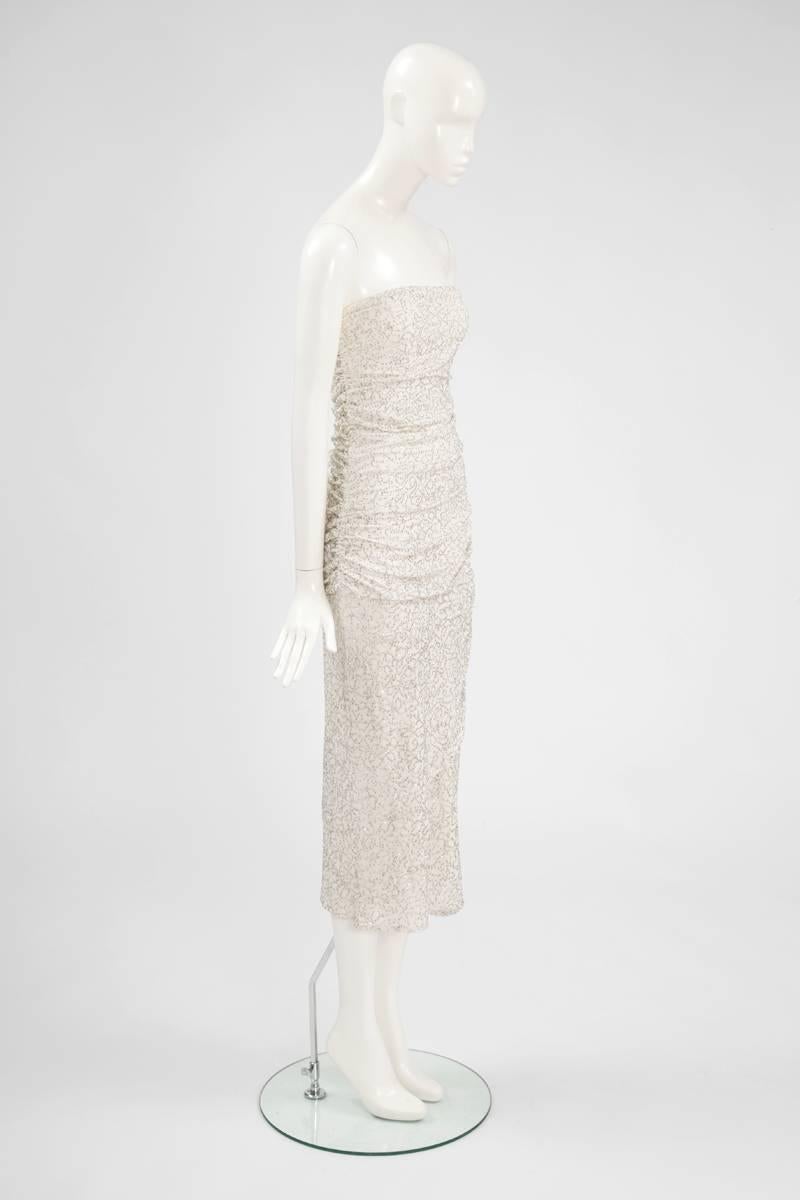 Zurück in die 80er Jahre mit diesem trägerlosen Kleid von Angelo Tarlazzi! Das Oberteil des Kleides aus Seidenjersey ist komplett gerafft und erweckt den Eindruck eines Zweiteilers. Der silberne Glitter ist direkt mit dem Seidenjersey verschmolzen.