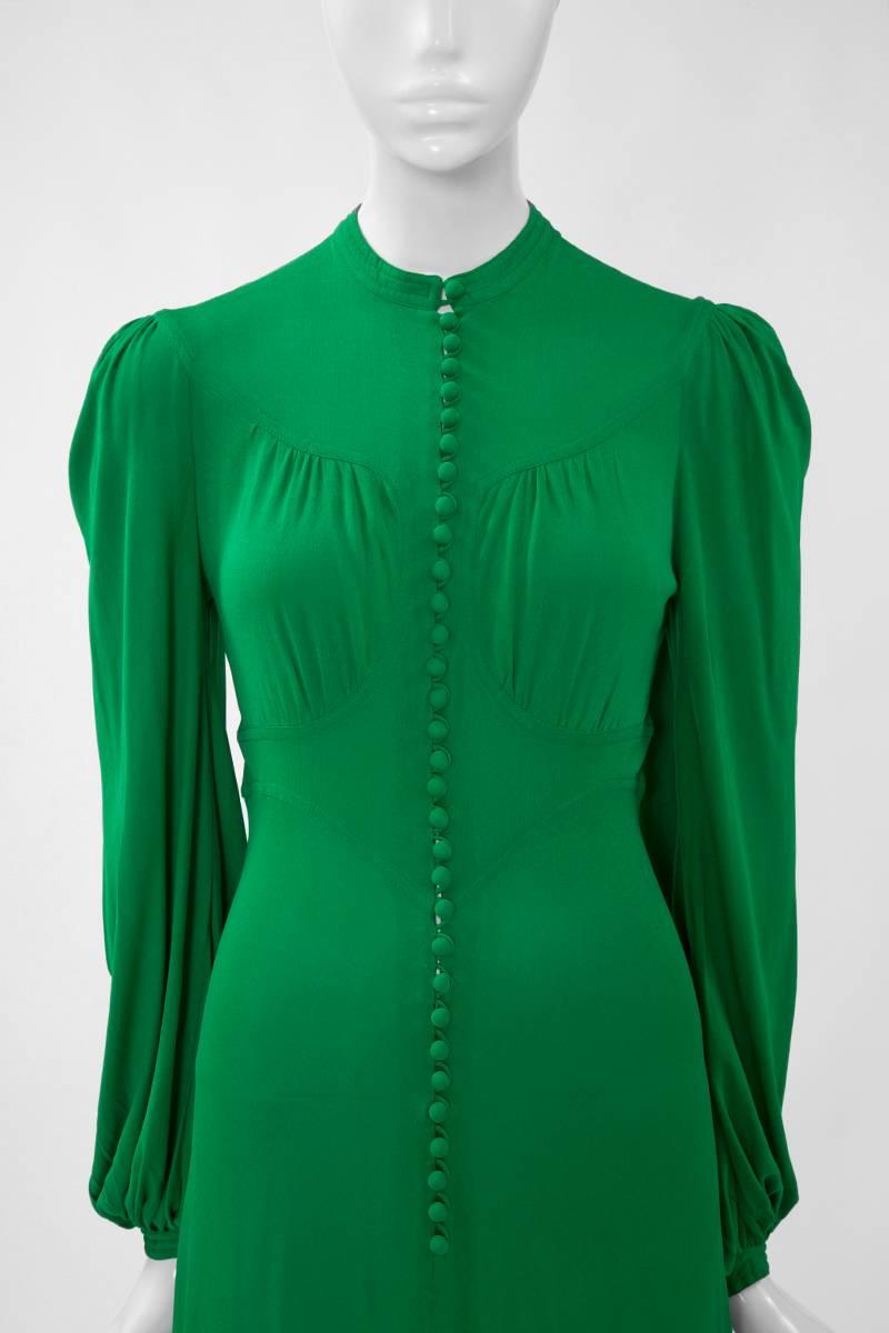Typical of Jean Muir, this 70’s vivid emerald jersey dress features thirty-two matching fabric covered buttons fastening to the front ! The subtle hourglass silhouette enhances the waist giving a flattering definition to the dress. Long blouson