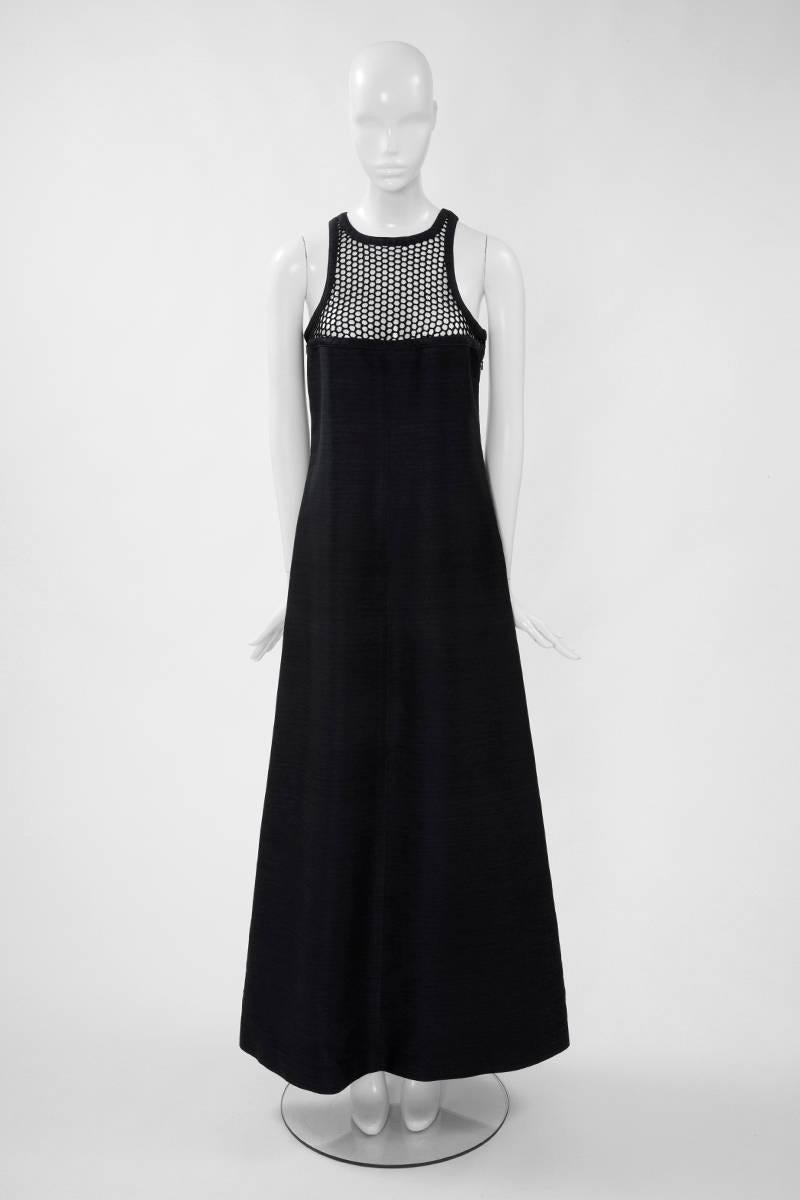 This late 60’s - early 70’s black cotton sateen Courreges maxi dress is a great example of the modernist design for which André Courrèges is famous. Of structured A-line silhouette and with unusual fishnet neckline, it is creating an advantageous