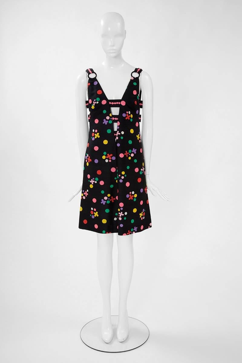 Constructed in silk and featuring multicoloured dots and flowers prints, this Catherine de Poorter sleeveless dress has four plunging necklines with decorative horizontal bands on the bust level. Classic 60’s A-line silhouette. This fantastic piece