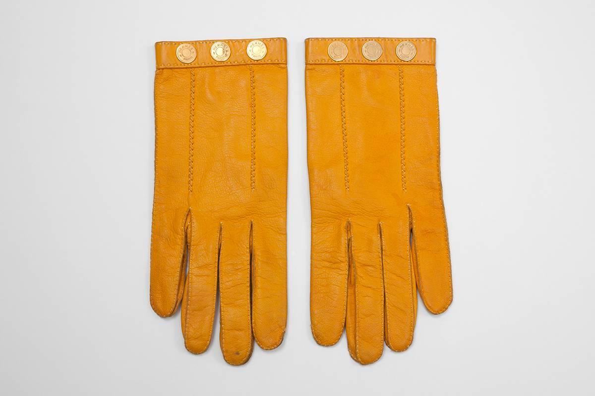 Made in France from refined sunny orange leather, these vintage silk-lined Hermès gloves are embellished with gilt metal round studs. Each stud is engraved with “Hermès Paris” inscription. Marked size 8 ; longest length (middle finger) approx. 22.2
