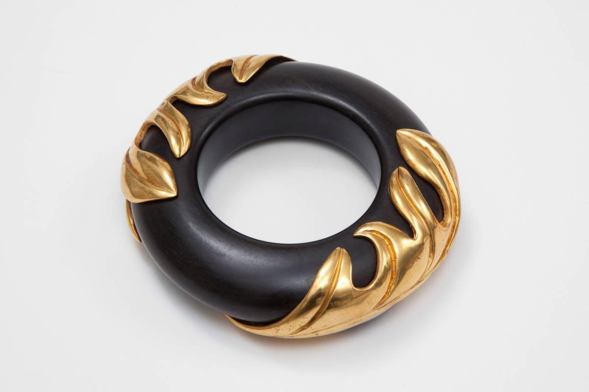 Perfect example of the famous 80's design by Isabel Canovas, this iconic bangle in teak wood and bronze overlays featuring large leaves is truly a striking element of any jewelry collection ! Of imposing scale, wear it solo or stacked with some