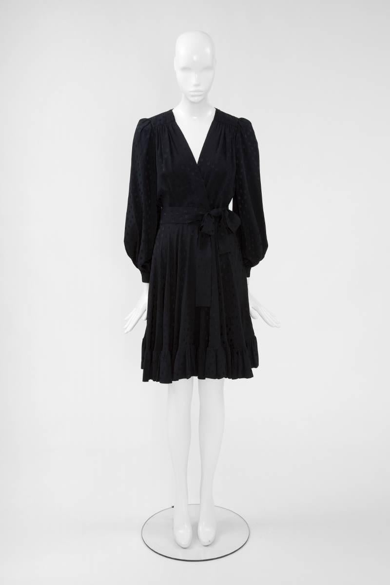 This late 70’s YSL dress has a flattering faux wrap silhouette. Constructed in black jacquard silk, the dress features a V-neckline and blouson sleeves. The shoulders are gathered so they slightly puff at the top. The long sleeves fasten at the cuff