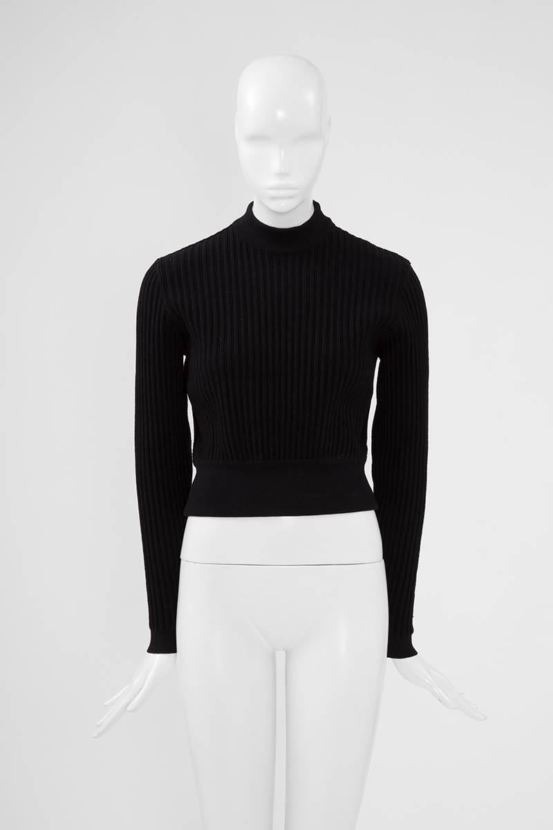 Cut from black ribbed stretch wool for a close fit, this 90’s Alaïa pullover features a high round neckline. Unlined, the pullover is a size medium but runs a bit small to size though the stretchy fabric will easily accommodate a size medium. Made
