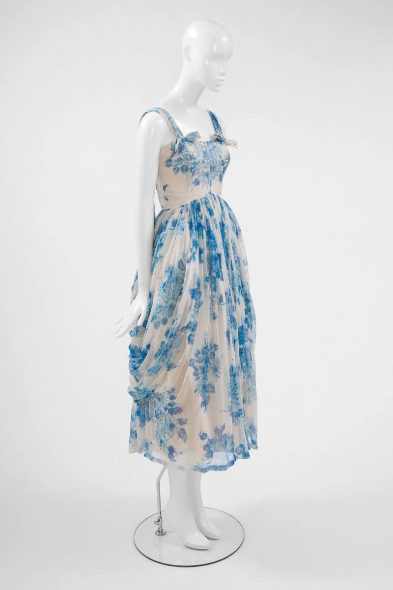 Absolutely perfect for the wedding season, this great unlabelled 50’s dress is made of refined bright blue on white printed silk chiffon. While the bust of the dress has a close-fitting cut, the bottom is constructed with a voluminous skirt. Coming