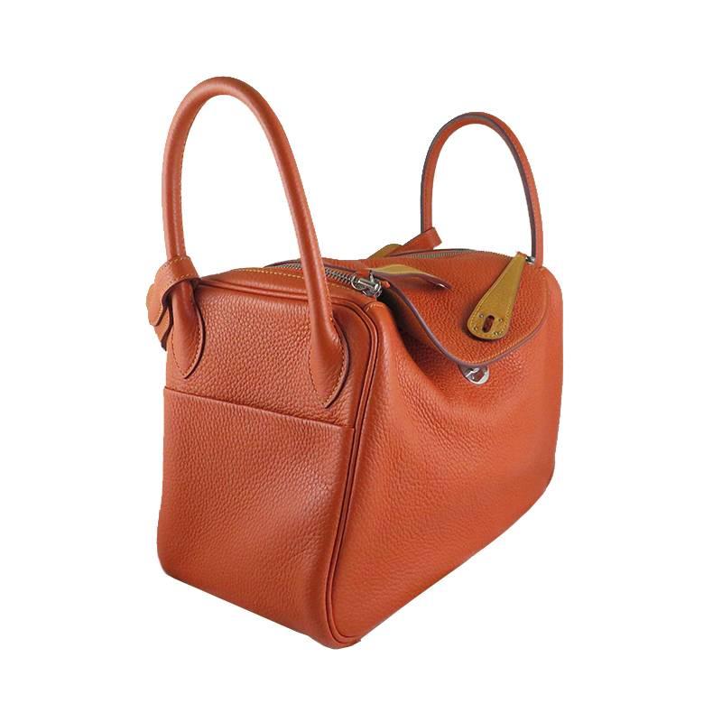 Rarely available in bicolor! It is in signature Hermes orange exterior and moutard interior on clemence leather with silver palladium hardware. The bag can be worn on the shoulders or carried on the wrists. It is in excellent condition without
