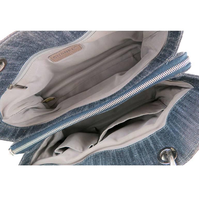 There are no visible stains or marks on the exterior denim fabric. Black lambskin handles shows no signs of wear. Silver hardware is shiny and has no fading or tarnishing. Fabric interior is clean and odorless. The bag has 1 exterior back pocket, 1