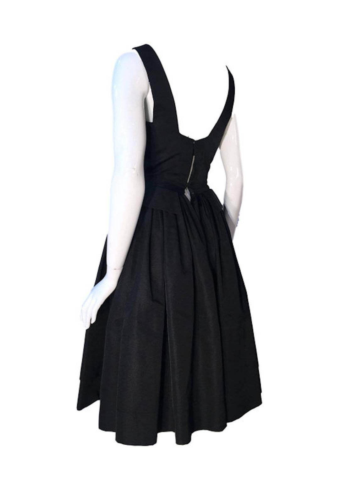 William Travilla 1950s vintage dress, made from black grosgrain silk, lined with silk chiffon, nipped in waist and flared skirt. Has bow trim on each strap on top of bust line.

Back popper and hook/eye fastening, a bit tight on the