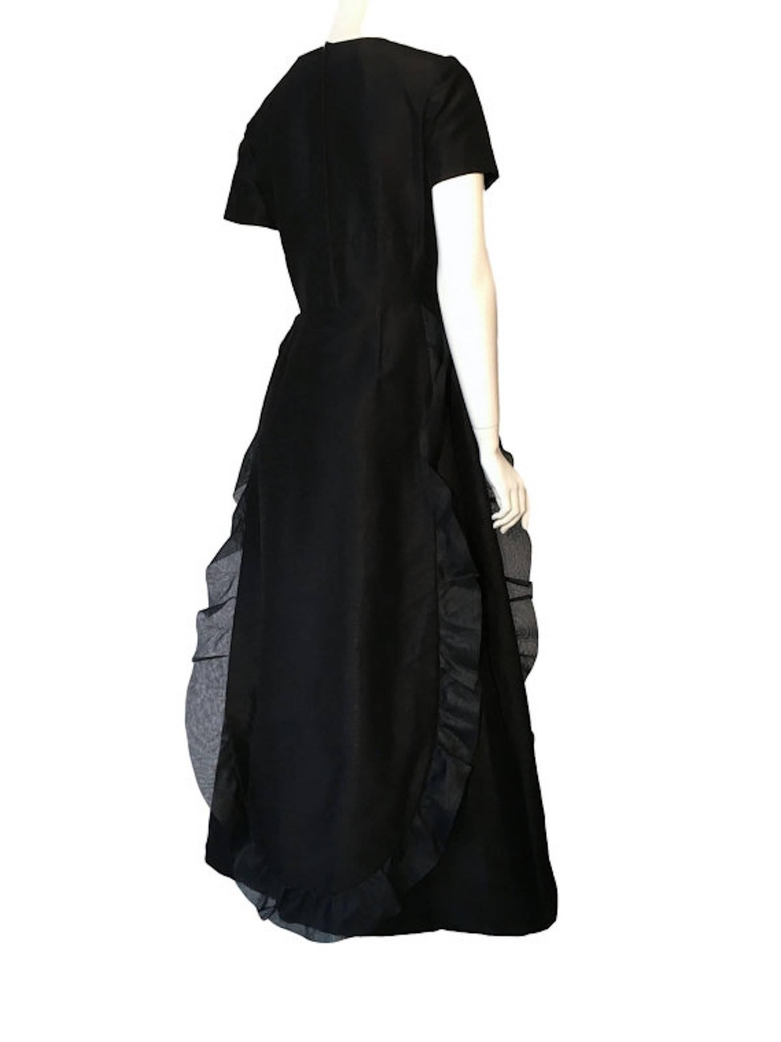 Black woven silk unlabelled black evening dress, 1960s era. Made at couture standard. Has front and back panel with ruffle trim. Metal zip and popper entry from the back. 

Size UK 8 measures 16 inches across bust, 13 inches across waist and 56