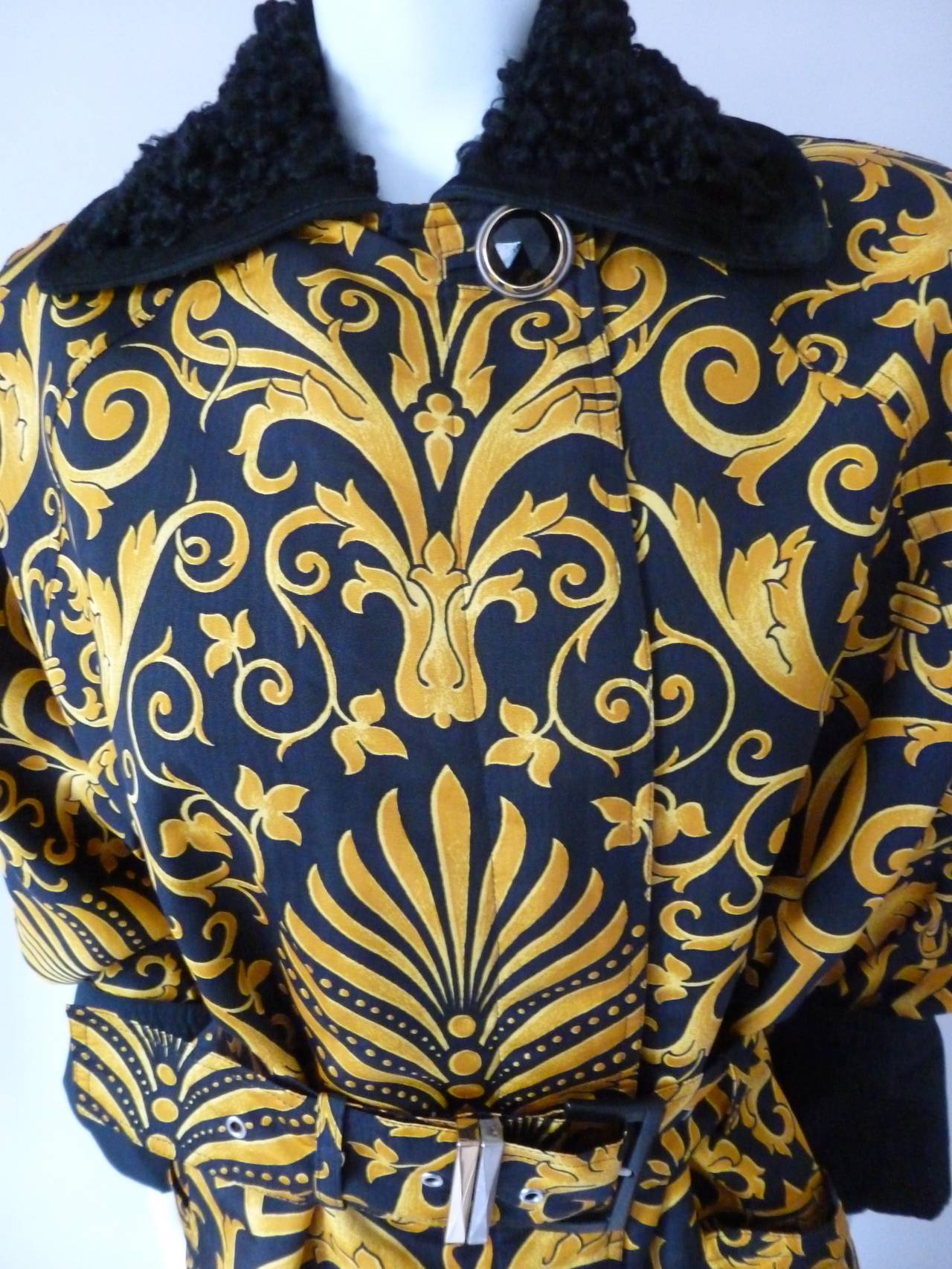 Iconic Gianni Versace gold and black Baroque printed silk belted raincoat from the Fall 1991 collection. The raincoat features an astrakhan collar and is secured at the neck by an oversized gold-tone metal and black glass button.

Marked an
