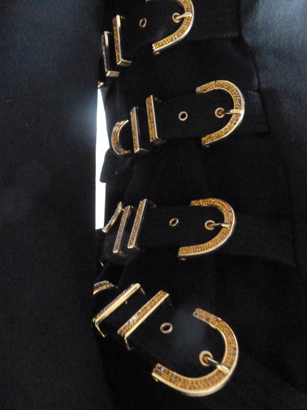 Gianni Versace Couture black silk and wool buckle bondage jacket from the Fall 1992 Bondage collection. The jacket is secured at the front by a series of gold-tone metal with gold strass buttons. The silk bondage buckles to each side feature