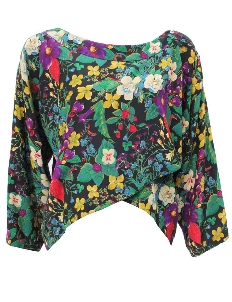 Gianni Versace Pret-a-Porter silk floral print wrap blouse from 1983. This very rare blouse features a vibrant floral print and is secured at the shoulder on one side by two metal and glass buttons.

Marked an Italian 44.

Fabric content - 100%