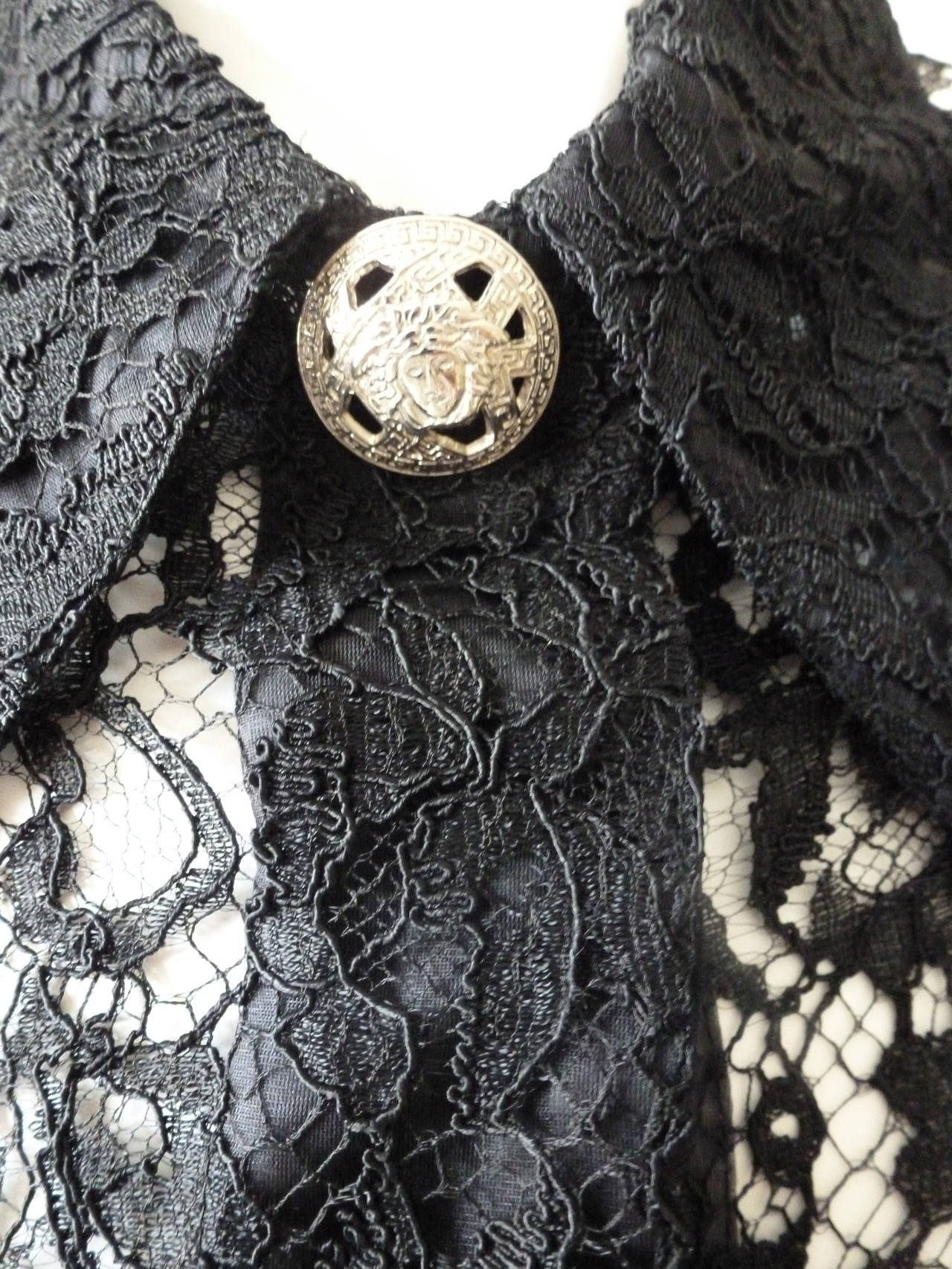 Iconic Gianni Versace Couture black lace blouse from the Spring 1994 Punk collection. The blouse is secured at the collar and the cuffs by a series of silver metal cut-out Medusa buttons.

The blouse featured in the advertising campaign for the