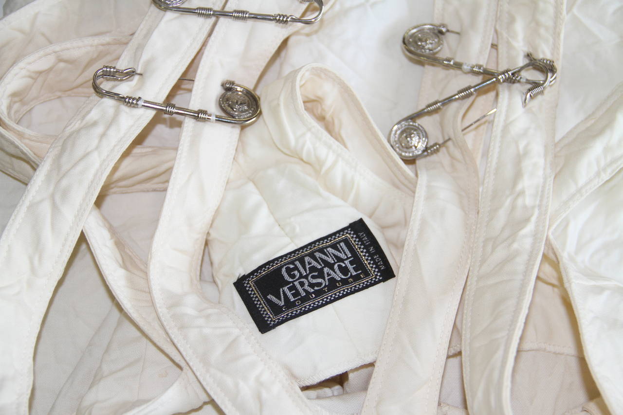 Very rare Gianni Versace cream wool safety pin jumpsuit from the Spring 1994 Punk collection.

The fabric of the jumpsuit is permanently creased, to further enhance the punk inspired look of the piece.

The jumpsuit was featured in the
