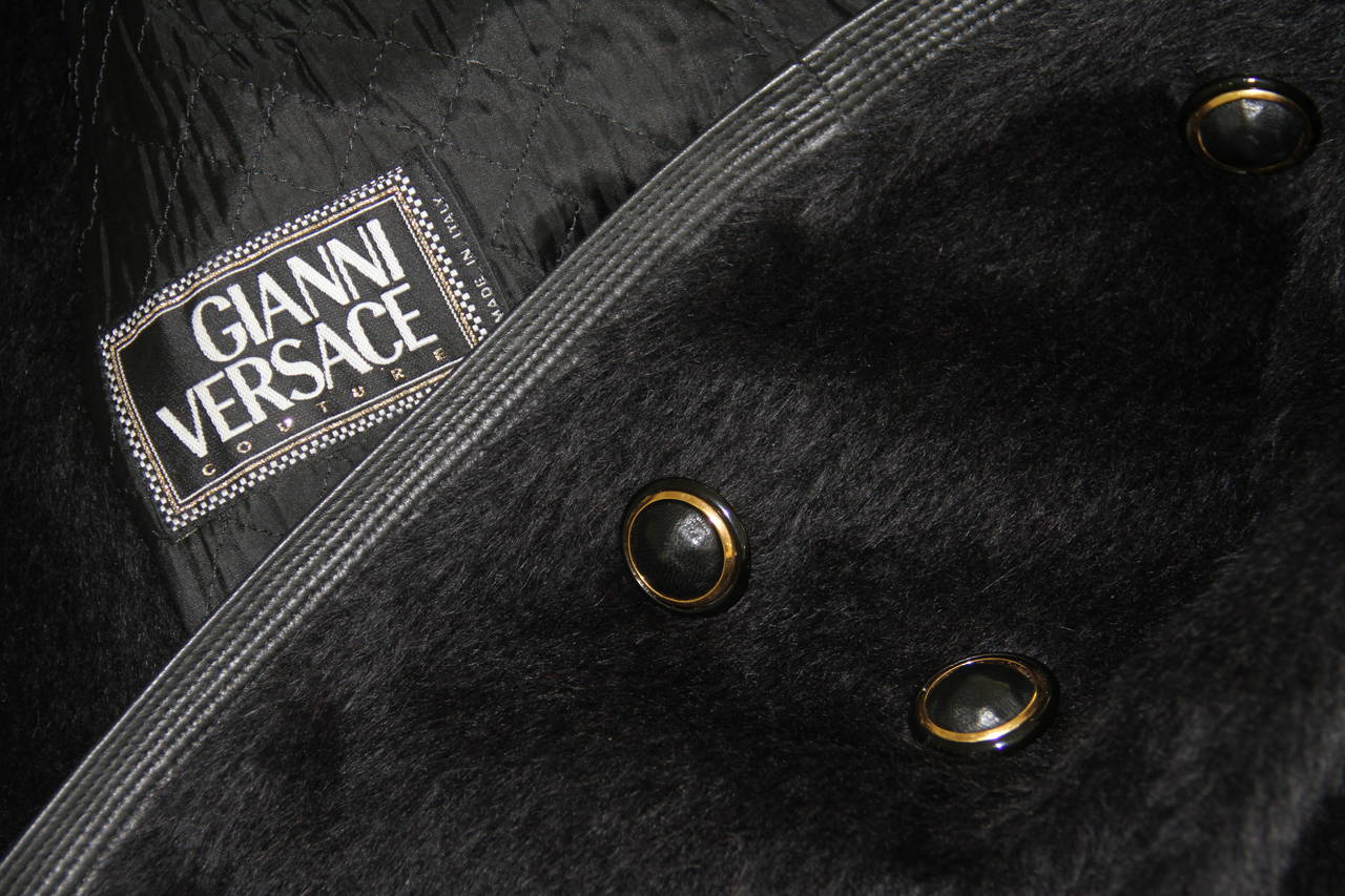 Gianni Versace black silk alpaca double breasted coat from the Fall 1992 Bondage collection.

The coat features leather cuffs and collar detailing, together with cowboy western gold-tone and silver-tone metal tips to the collar and gold-tone and